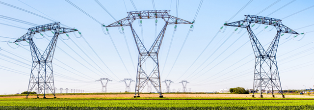 Panoramic view of a row of electricity pylons in the countryside.
